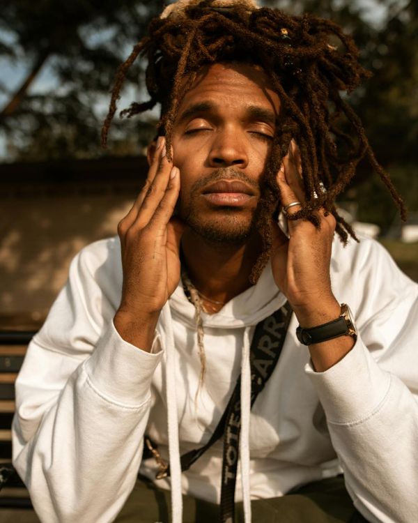 A person meditating peacefully outdoors with a calm expression.