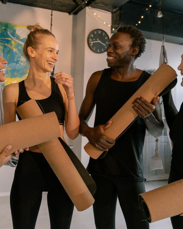 Diverse group of people smiling and preparing for a yoga class.